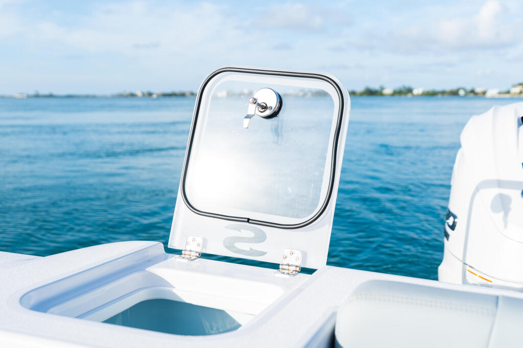 Boat windshield with chrome frame and mounting hardware overlooking calm blue water and distant coastline