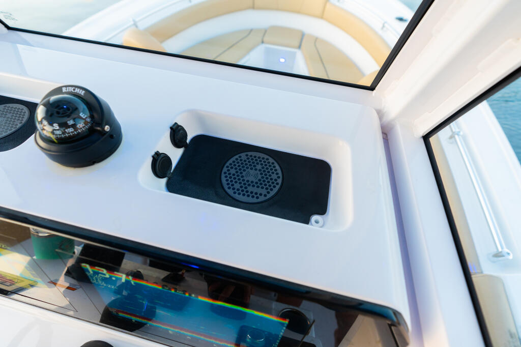 Helm console detail showing Ritchie compass, audio speaker system, and 12V power receptacles
