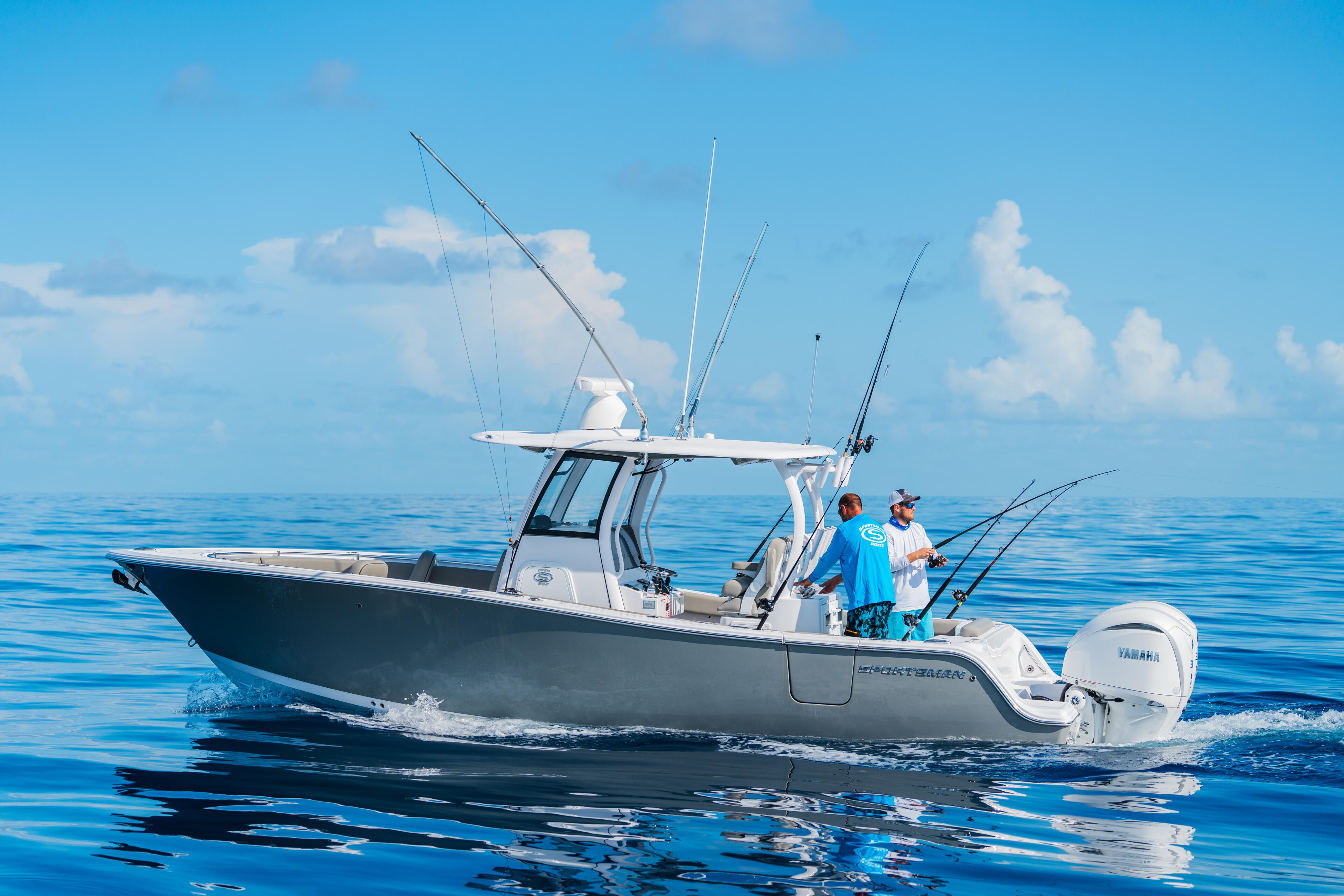 Two anglers fishing offshore on a center console boat with multiple fishing rods rigged in calm blue waters