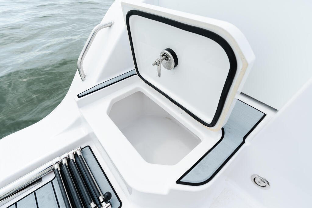 Open cabin door on white sport fishing boat with black trim overlooking calm water