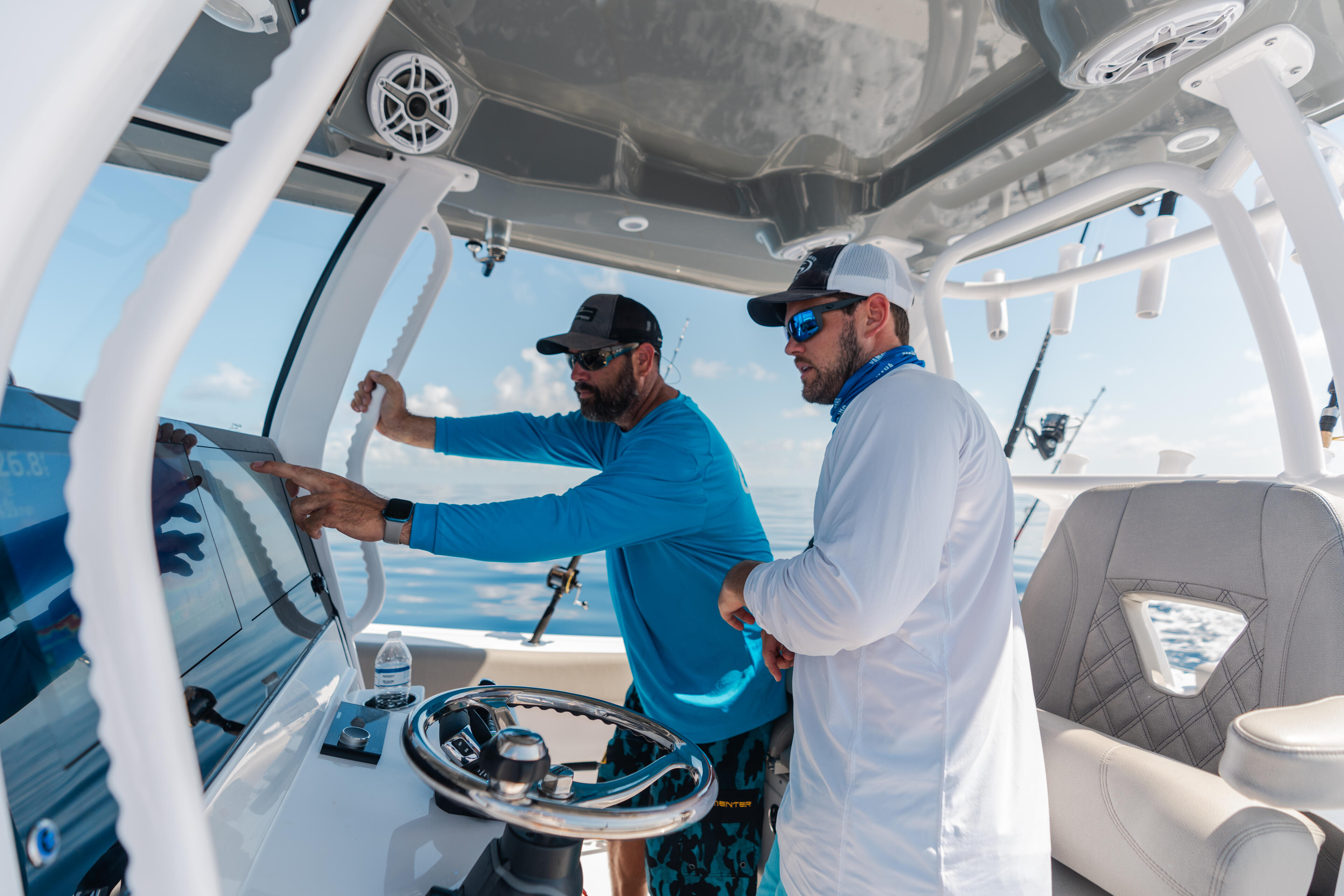 Two anglers at the helm of an offshore fishing boat on a clear day