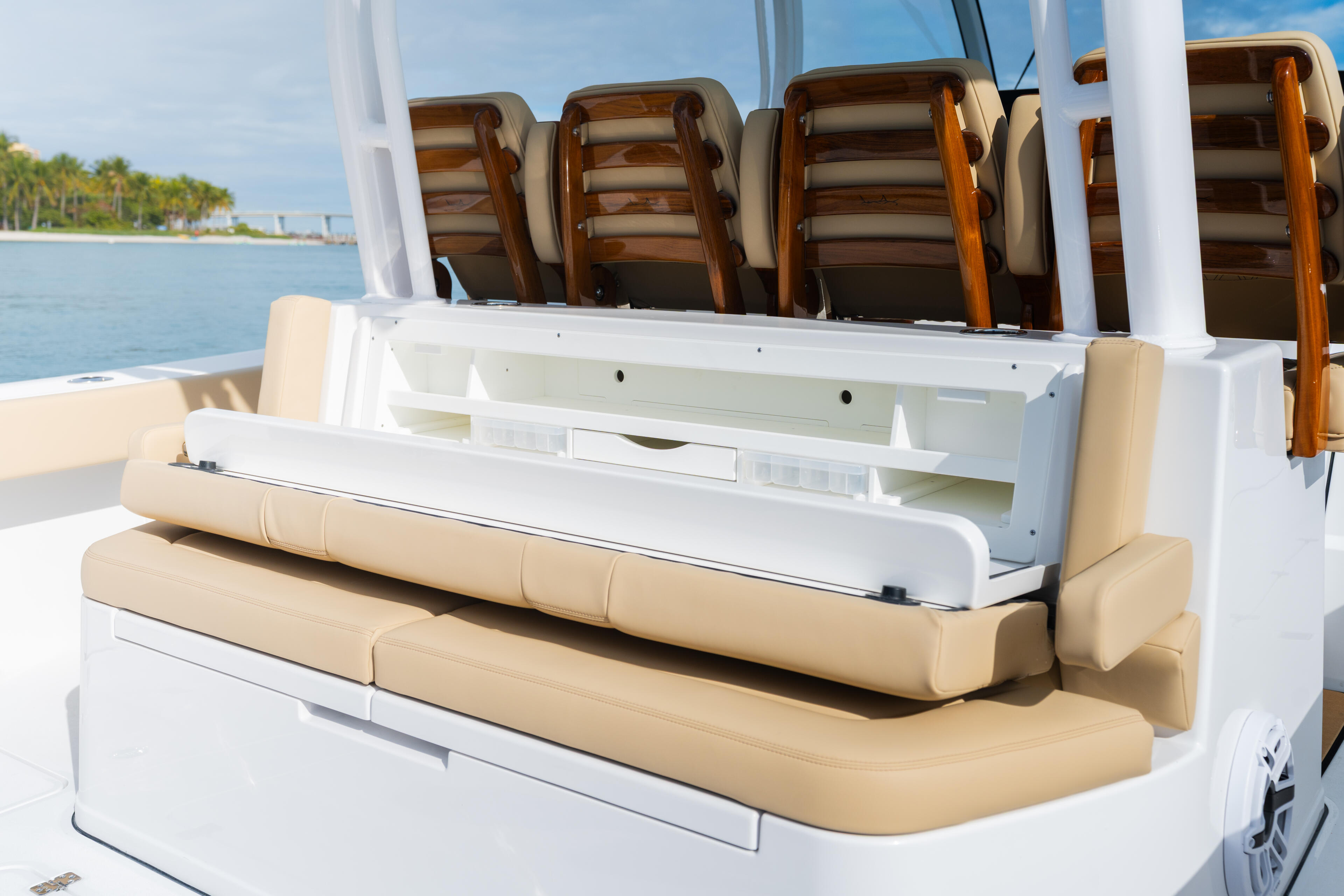 Tan and white cushioned seating with wood-trimmed backrests and a central storage console on a center console boat