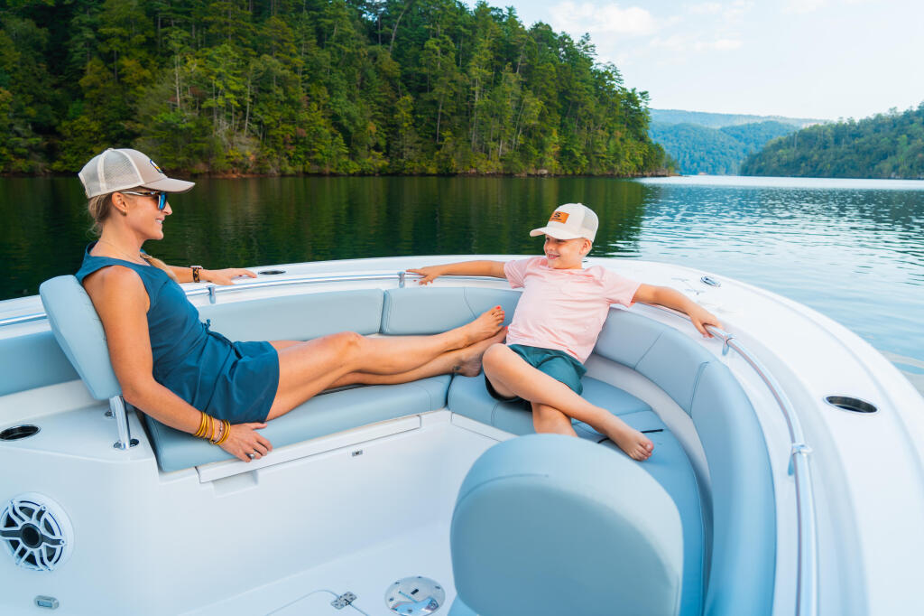 Woman and child relax in comfortable bow seating while cruising a pristine mountain lake surrounded by forested shores
