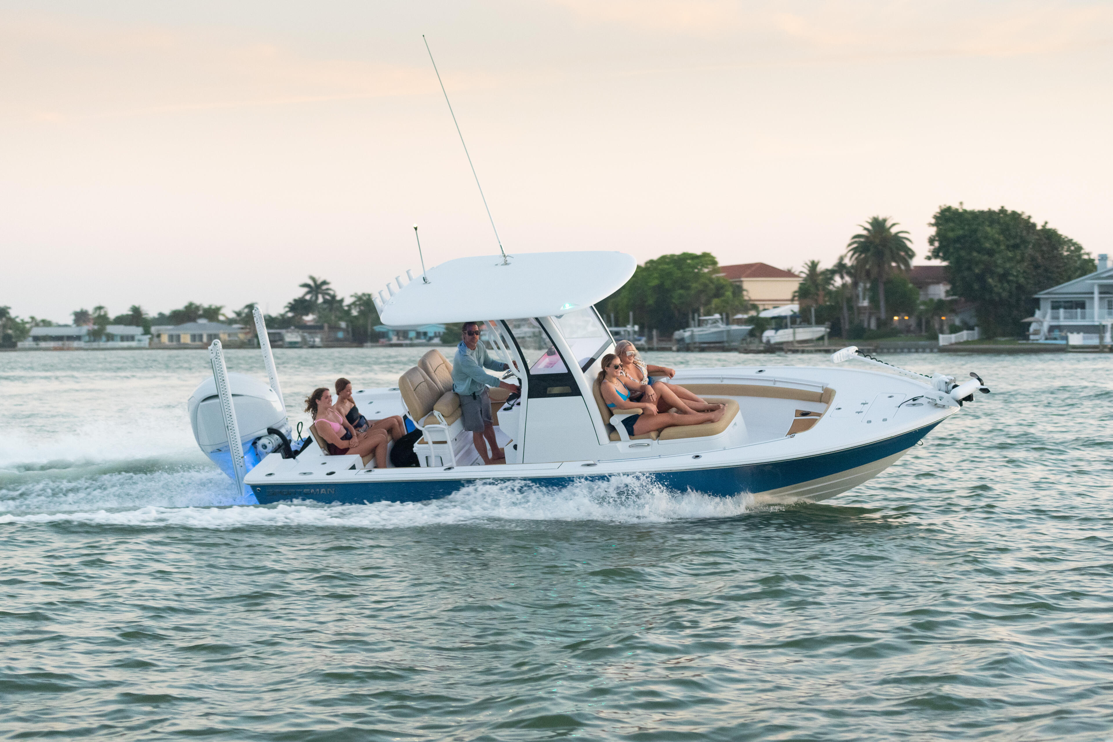 Family and friends enjoying a recreational boat ride in shallow coastal waters near residential homes