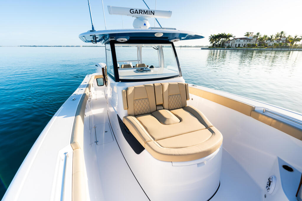 Center console fishing boat with tan seating, hardtop, and Garmin electronics anchored in shallow tropical waters