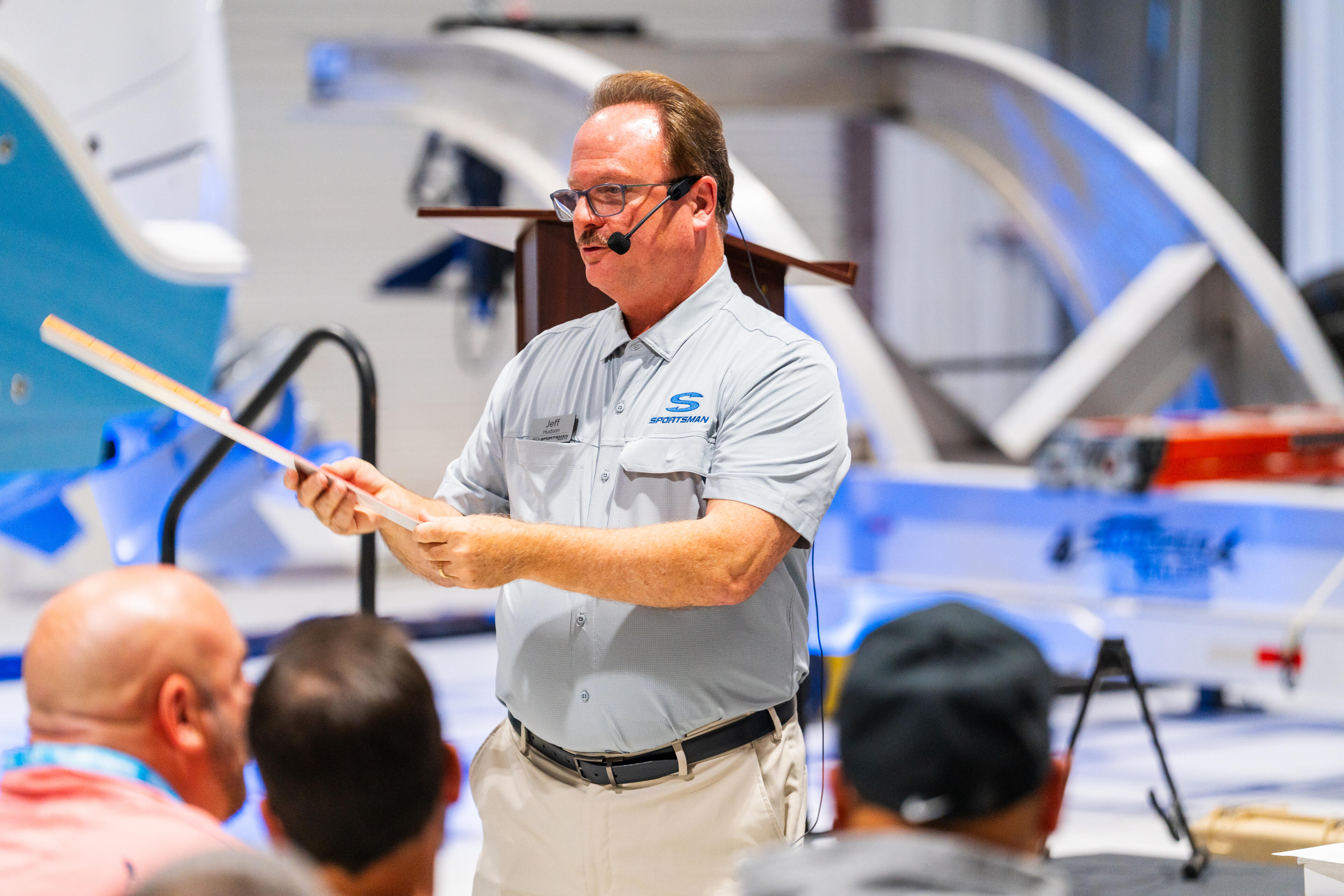 Dealer or salesman presenting to customers in a showroom filled with blue and white boats