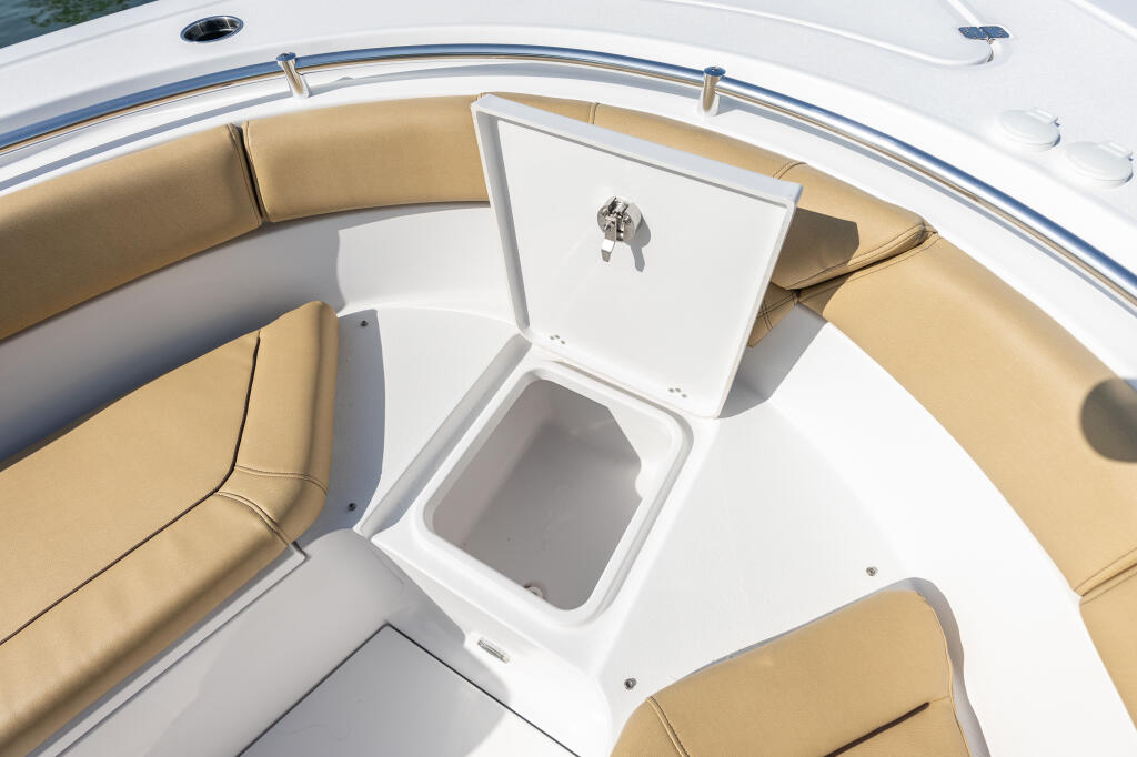 Overhead view of center console bow seating with tan cushions, white fiberglass, and storage compartment with livewell