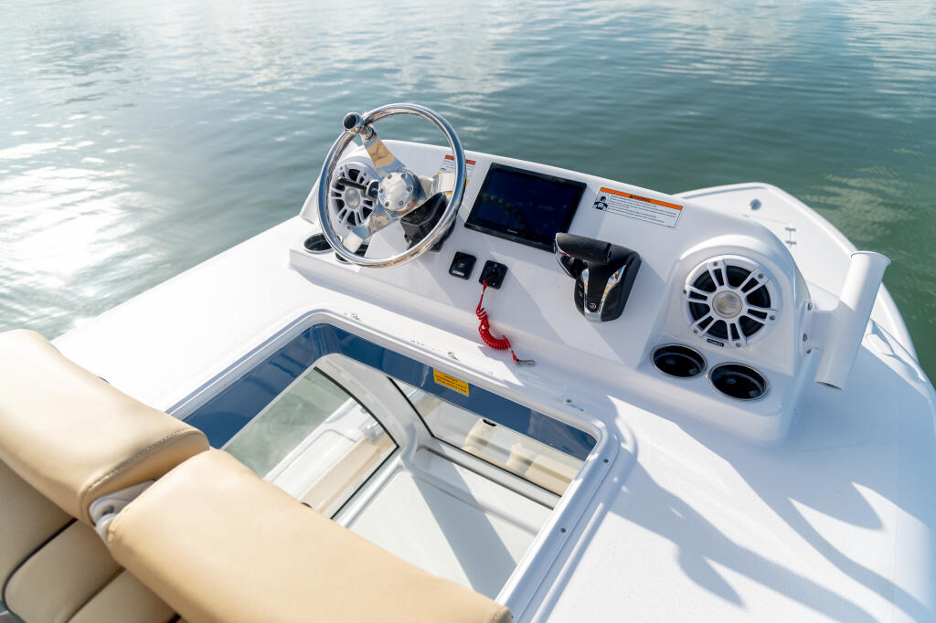 Helm station with steering wheel, digital display, and dual controls on a modern center console boat