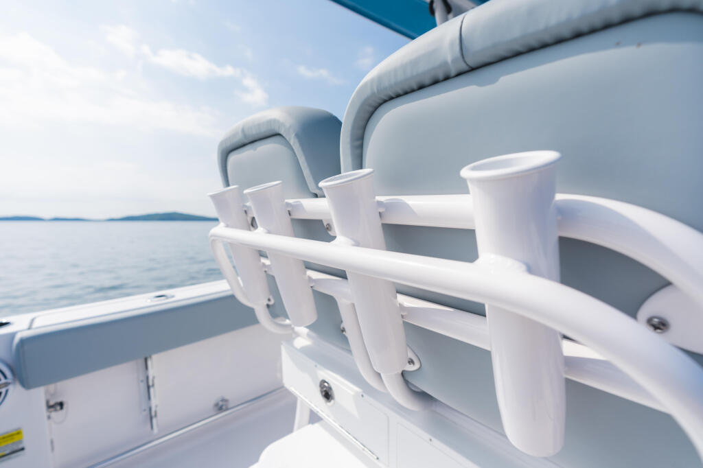 White cup holders and railing on boat console with calm lake and distant shoreline in background