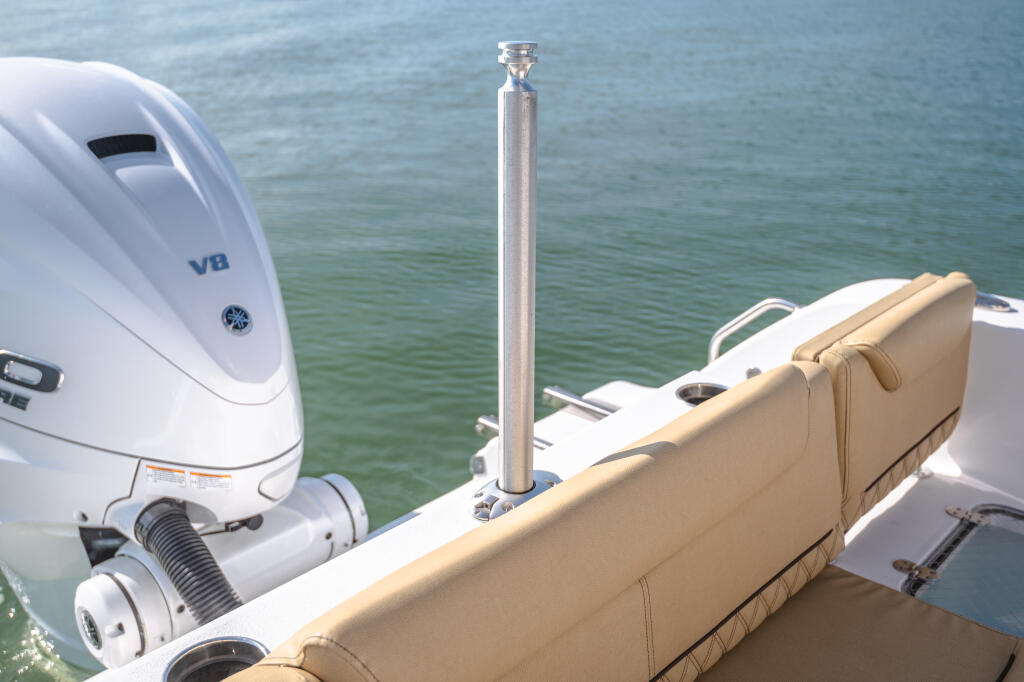 White outboard engine and telescoping ski tow bar mounted on boat transom with tan cushioned seating
