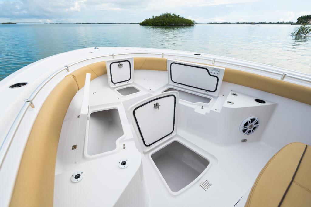 Center console boat cockpit with tan upholstered seating, white fiberglass deck, and multiple storage compartments overlooking mangrove islands