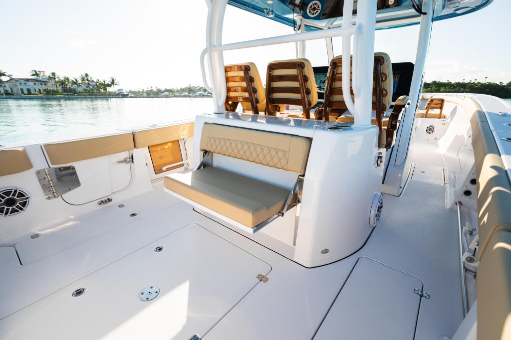 Spacious boat deck with tan seating, cooler storage, and hard-top canopy overlooking waterfront homes