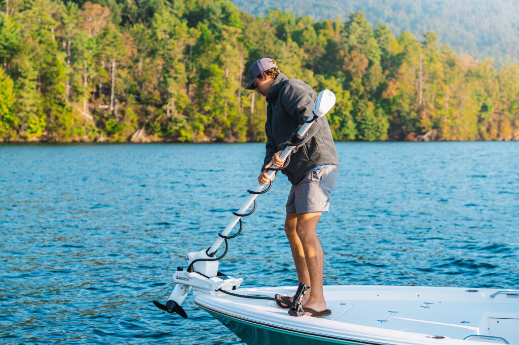 Angler standing on boat deck deploying a white Garmin trolling motor in a mountain lake