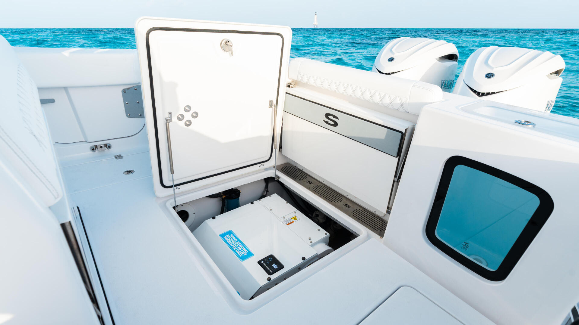 Open storage compartment with electronics and equipment visible inside a white center console boat
