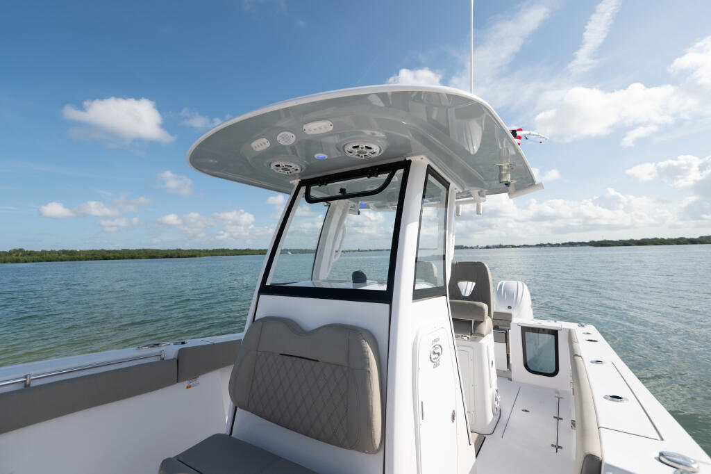 Center console boat with hard-top canopy cruising through calm waters under clear sky