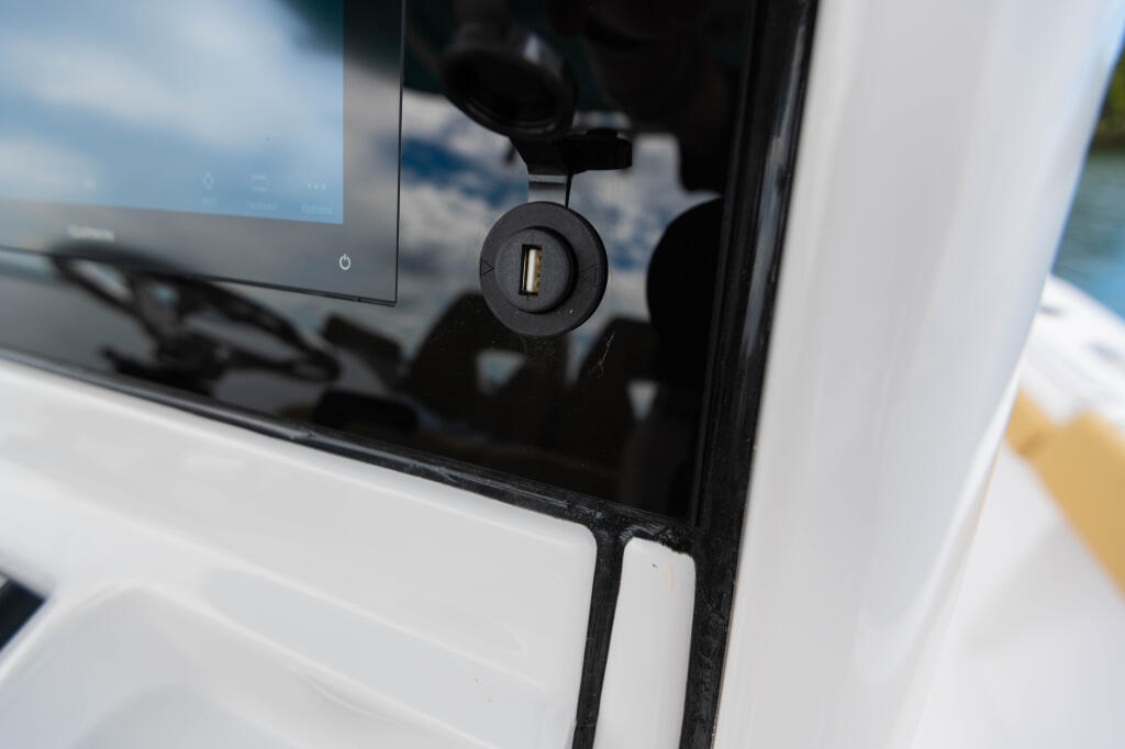 USB charging port mounted on boat dashboard with water and sky visible through windshield