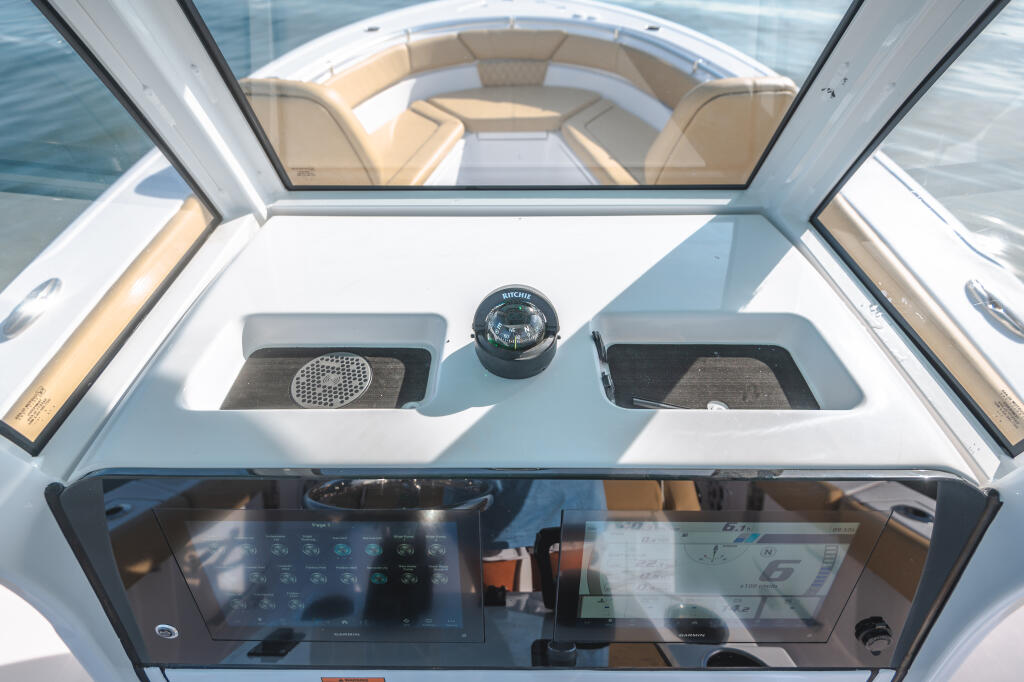 Center console helm with dual touchscreen displays, compass, and storage compartments overlooking the bow