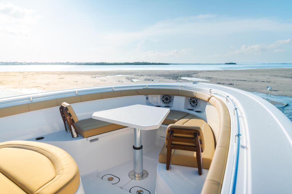 Boat's aft deck with tan seating, table, and water view of shallow sandbar