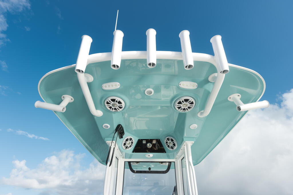 Overhead view of boat's hard-top with white rod holders, electronics, and ventilation exhausts against blue sky
