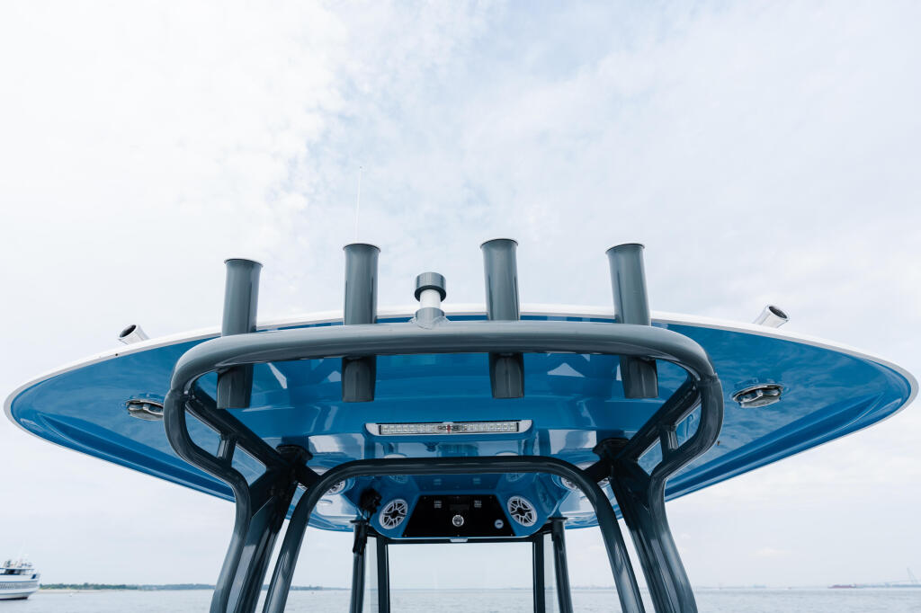Boat hardtop with four vertical posts and curved windshield viewed from behind the helm