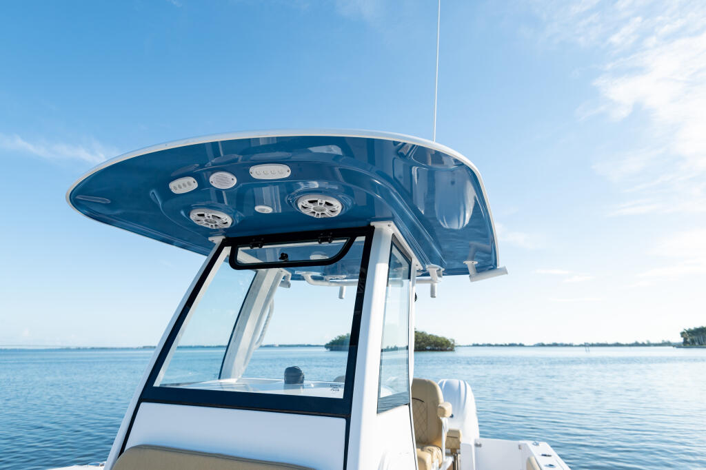 Hard-top with integrated tempered glass windshield and manual vent on center console boat overlooking calm water