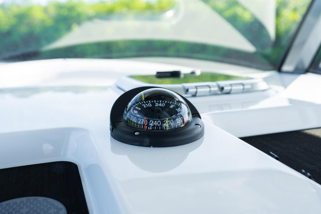 Compass mounted on white console of Open 322 boat with water and shoreline visible in background