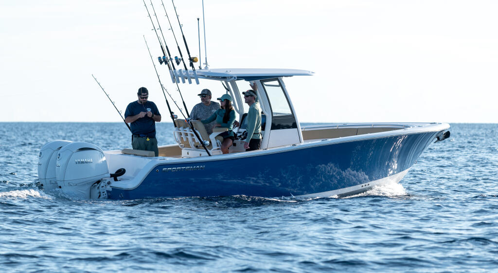 Blue and white center console fishing boat running offshore with anglers holding fishing rods