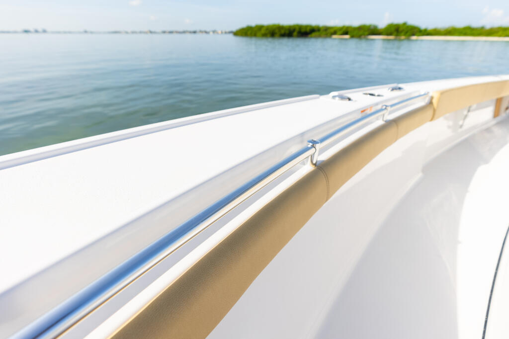 Boat's bow railing and deck with calm water and mangrove shoreline in background