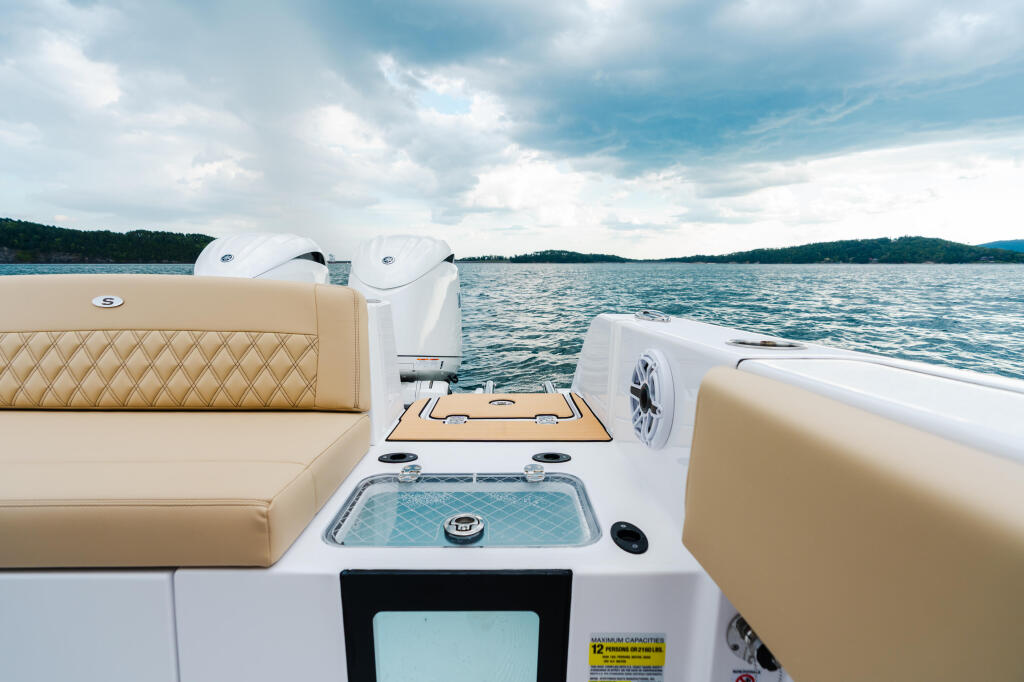 Stern deck of a center console boat with tan quilted seating, white hardtop, and water views