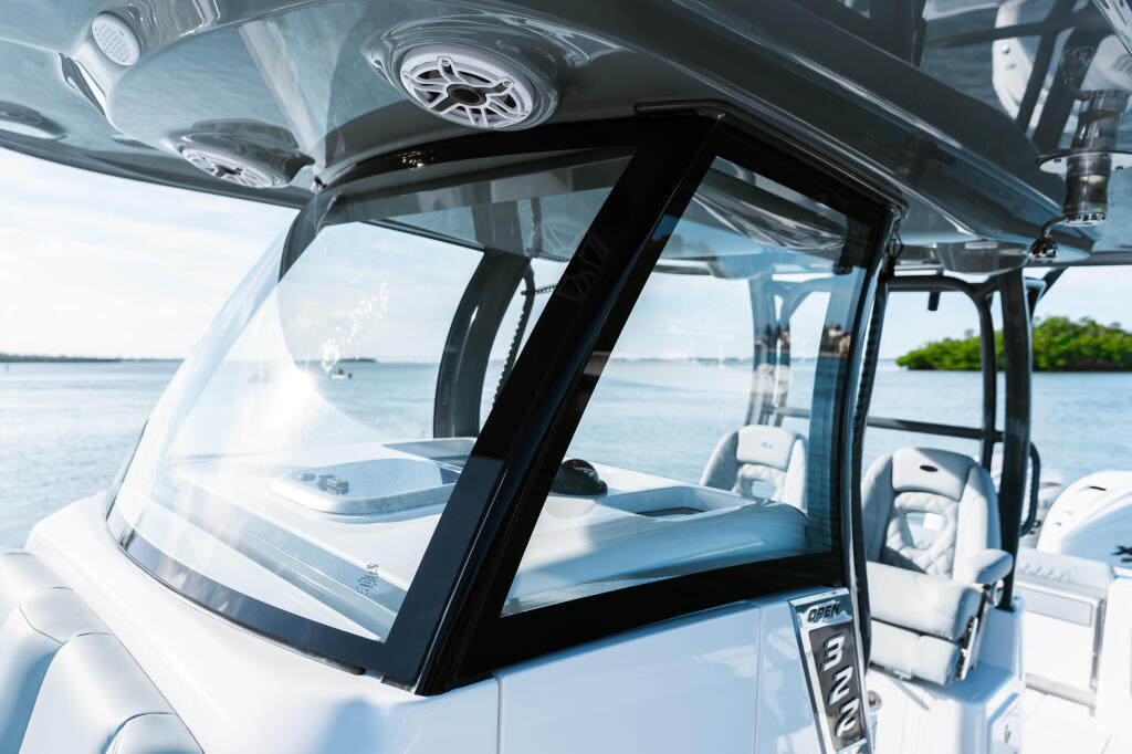 Windshield and helm view of a center console boat anchored in calm blue waters with mangroves visible in the distance