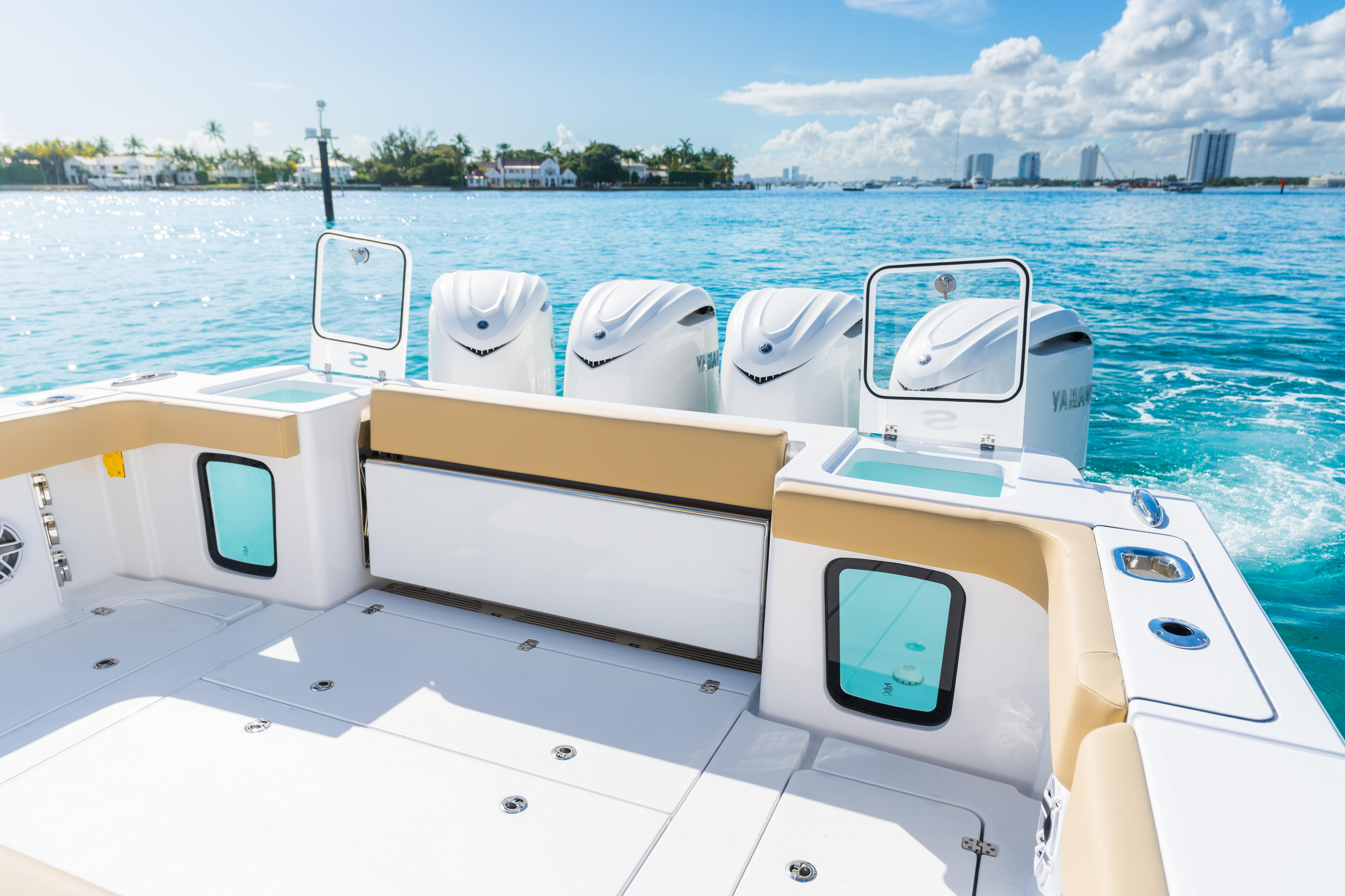 Helm station and seating area of a center console boat with white Yamaha outboards and coastal cityscape in background
