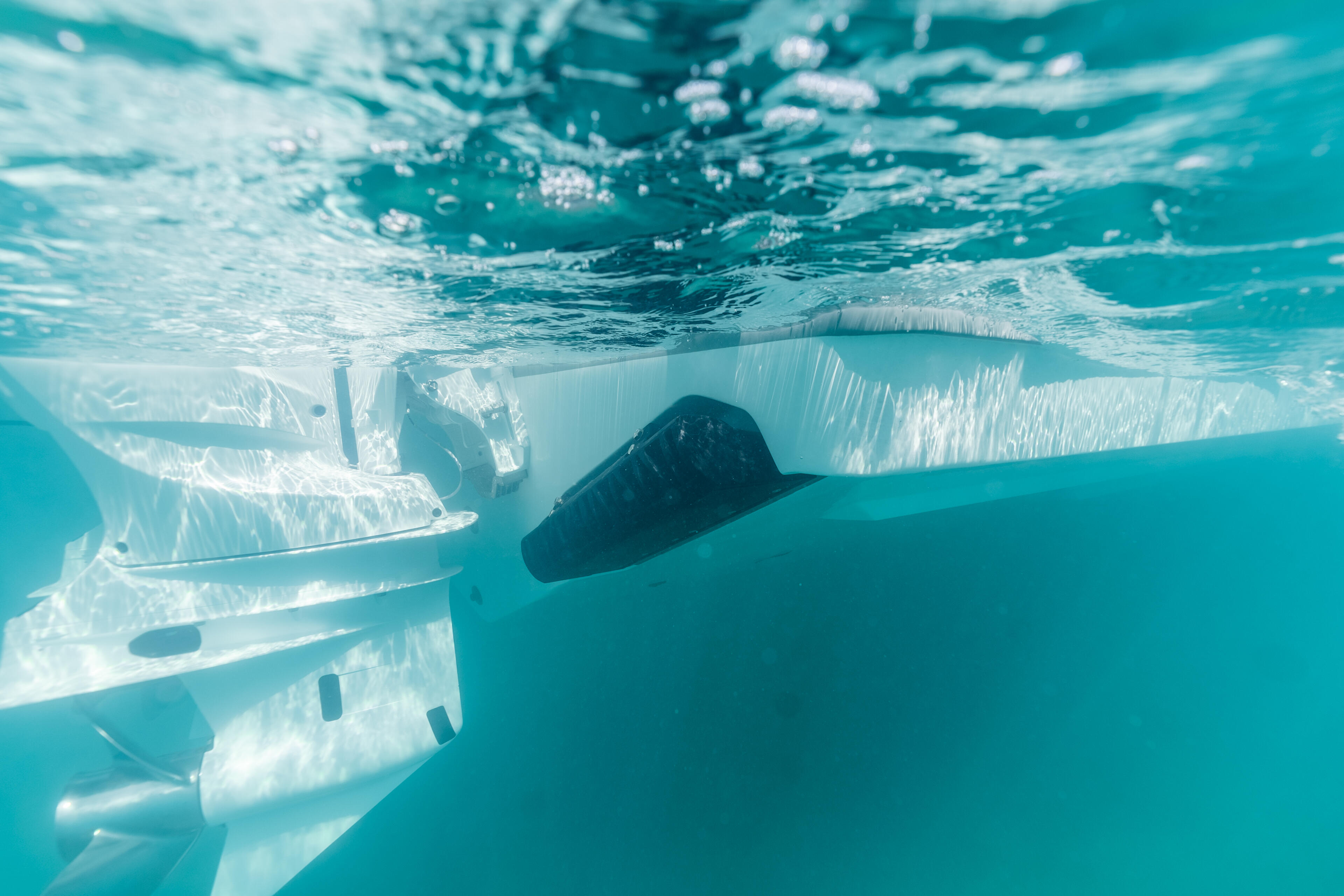 Underwater view of a boat's hull and propellers from below the surface in clear turquoise water