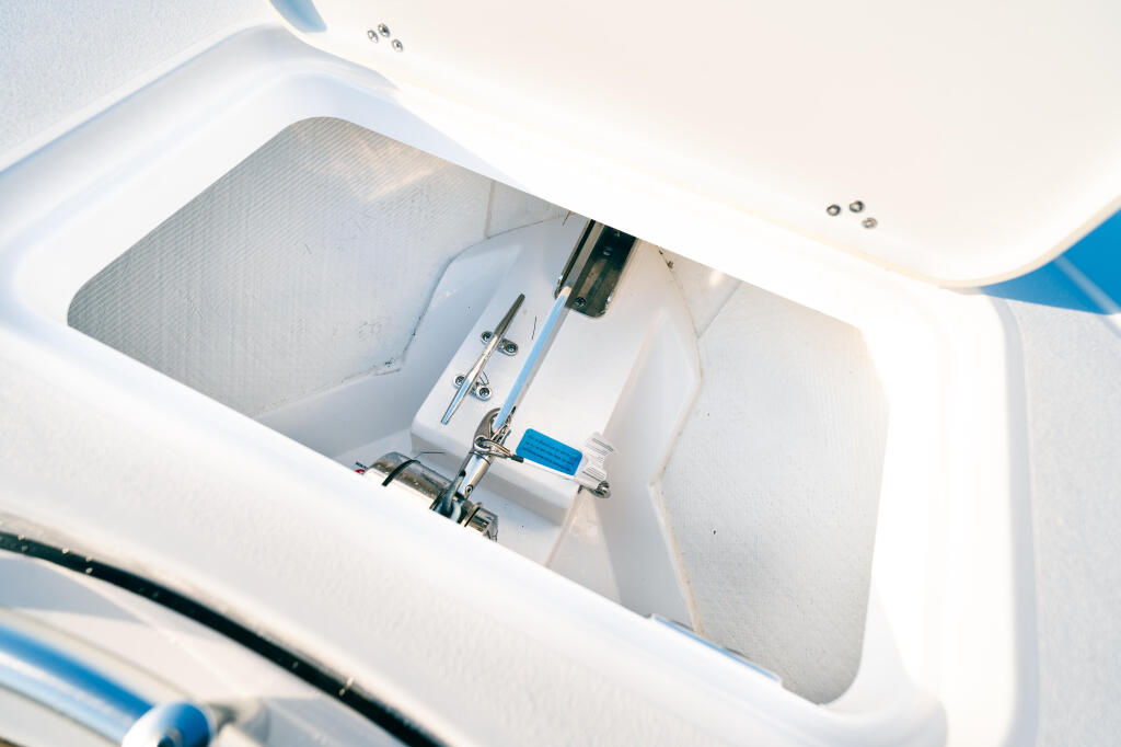Overhead view of an open boat storage compartment with white fiberglass interior and blue accents