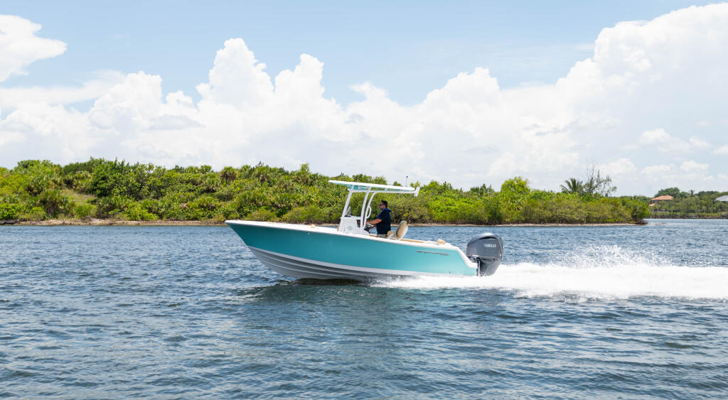 Turquoise and white center console boat running at speed near mangrove shoreline with white hard-top canopy