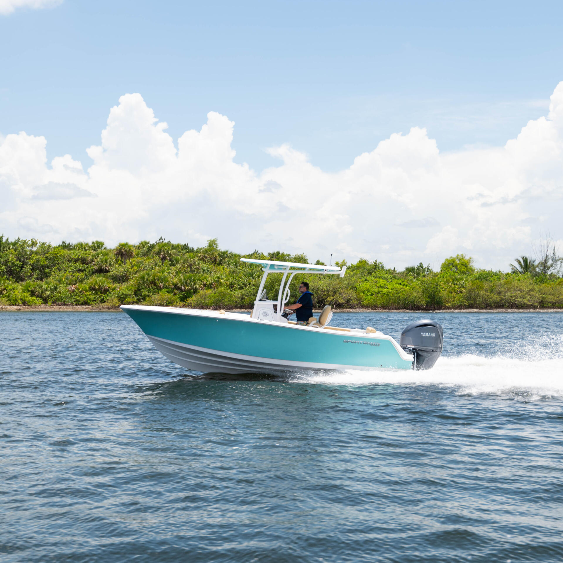 Turquoise and white center console boat running at speed near mangrove shoreline with white hard-top canopy