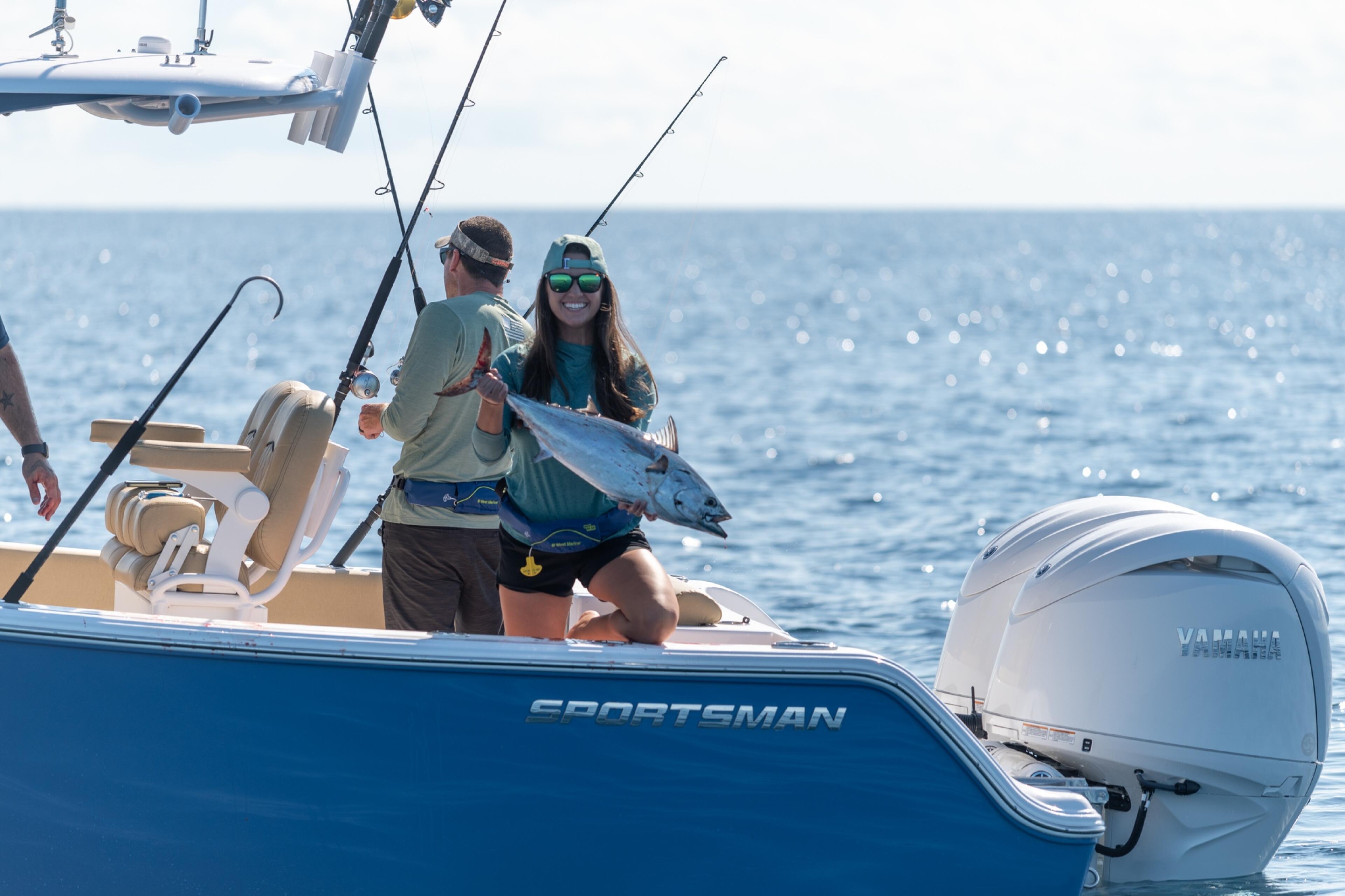 Anglers holding a freshly caught fish on a Sportsman boat in offshore waters
