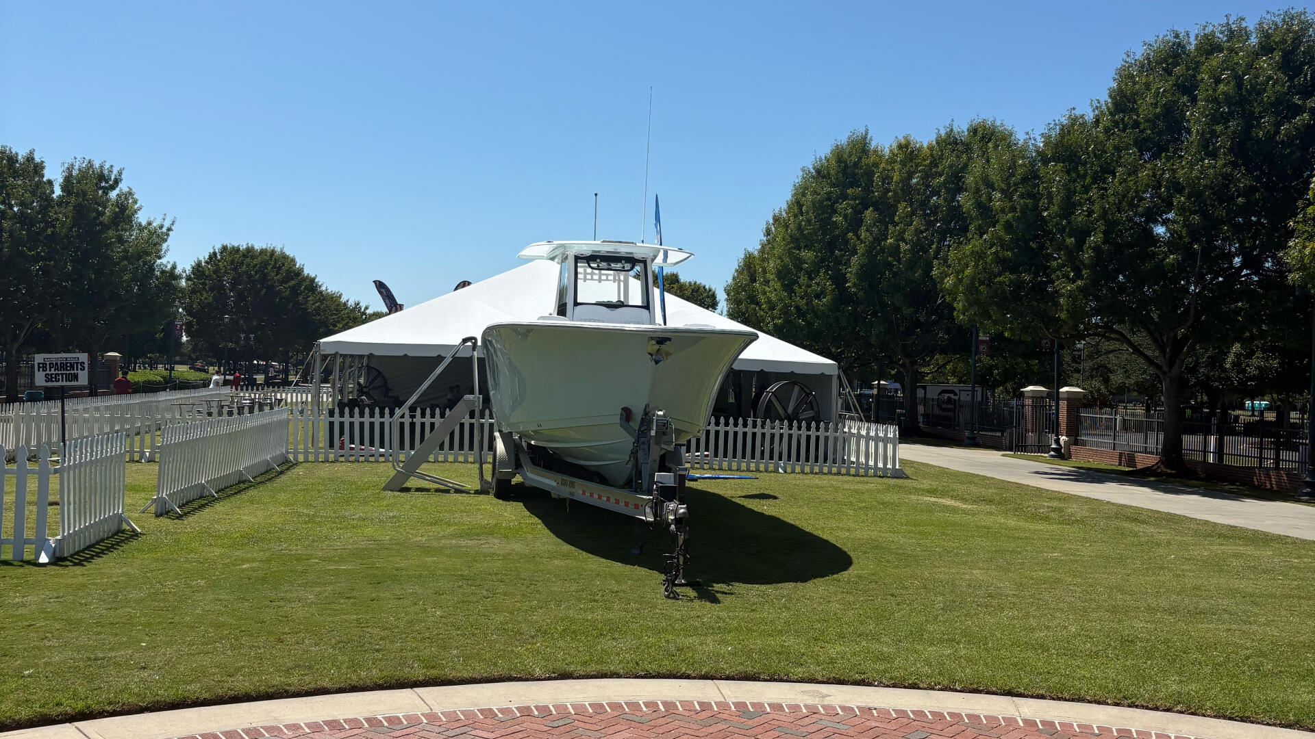 Center console fishing boat with hard-top displayed on grass and brick patio at marina event