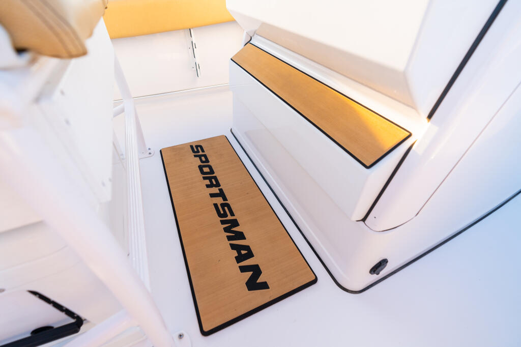 Sportsman branded anti-fatigue mat installed at the helm console of a boat with white interior and gold accents