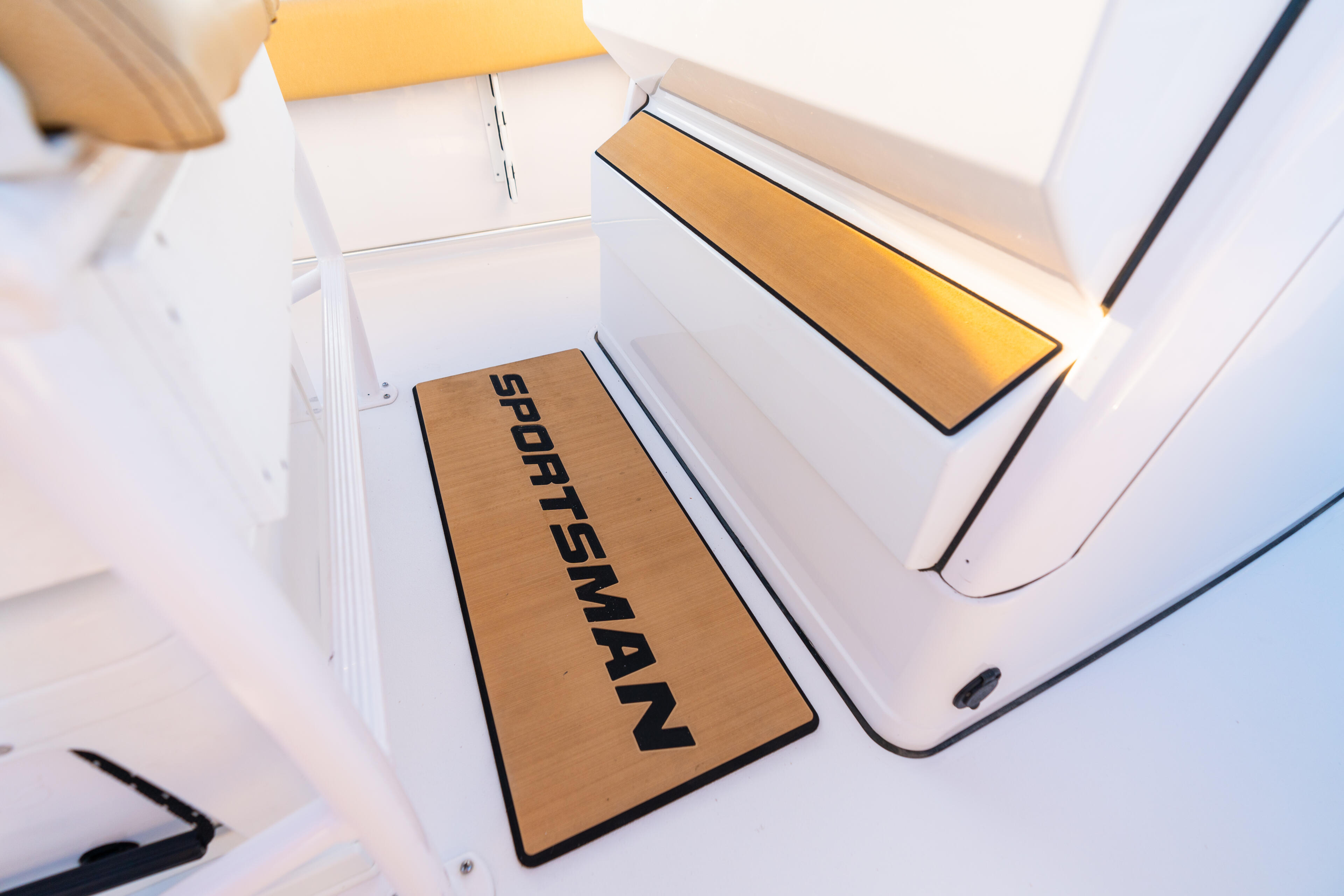 Sportsman branded anti-fatigue mat installed at the helm console of a boat with white interior and gold accents