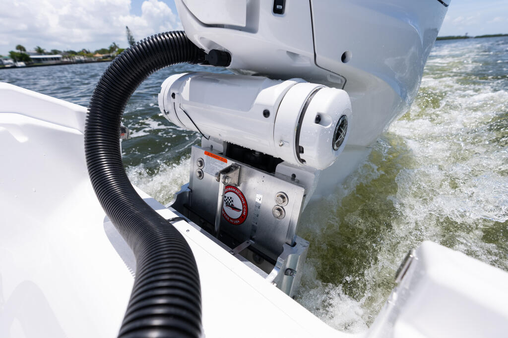 Jack plate and trim pump mounted on boat transom with water and shoreline in background