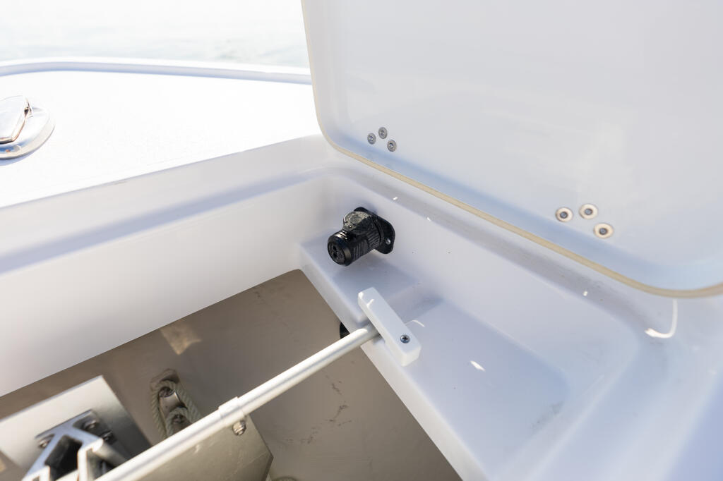 Open storage compartment with trolling motor plug and electrical connections on boat console