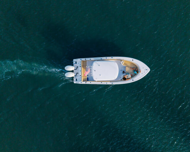 White center console boat running offshore with visible dual engines and full seating capacity