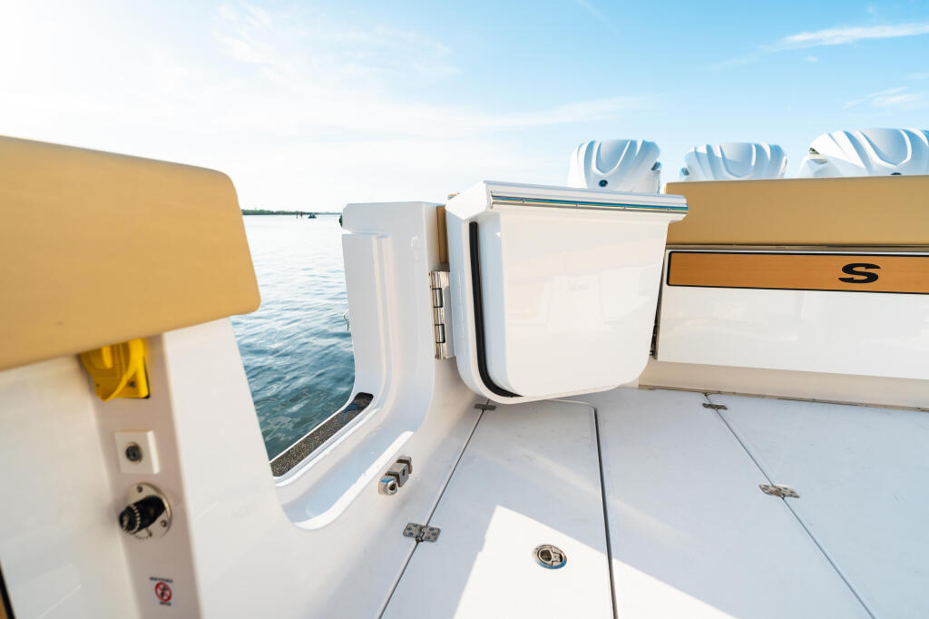 Boat deck with white storage locker and tan seating along calm blue water