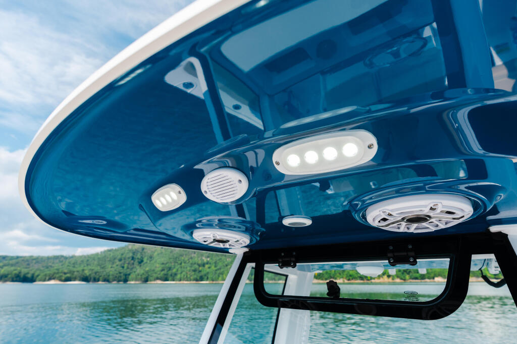 Hard-top boat canopy with LED lighting and ventilation speakers overlooking calm lake waters
