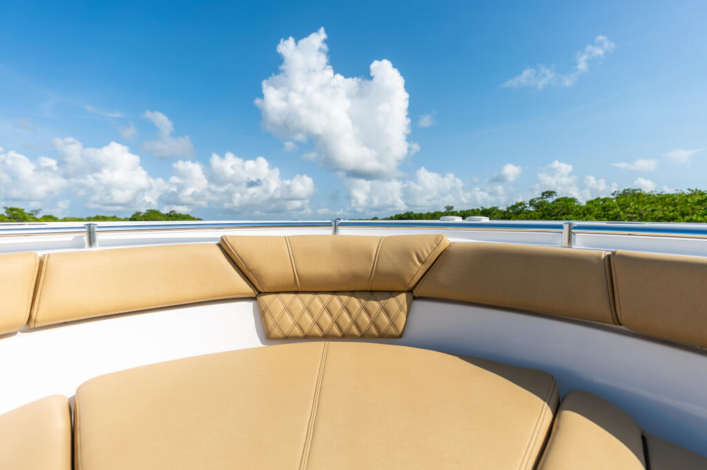Tan upholstered bow seating with water and mangrove shoreline under blue sky