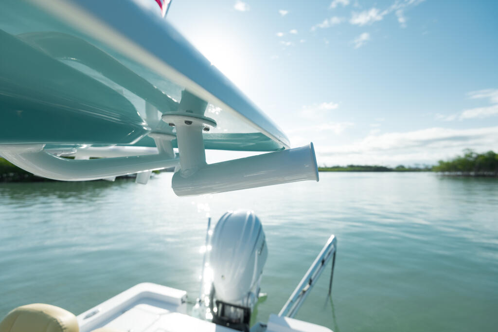 Close-up view of boat's outboard motor and propeller with calm water and mangrove shoreline in background