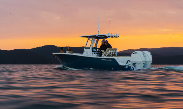 Sportsman center console boat anchored in calm water at sunset with mountains silhouetted in background