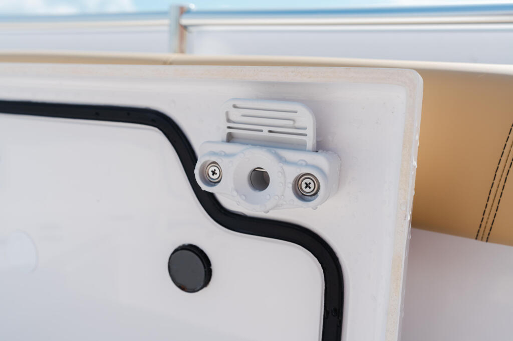 Close-up of boat interior hardware showing white mounting bracket with screws and black cable routing along white panel