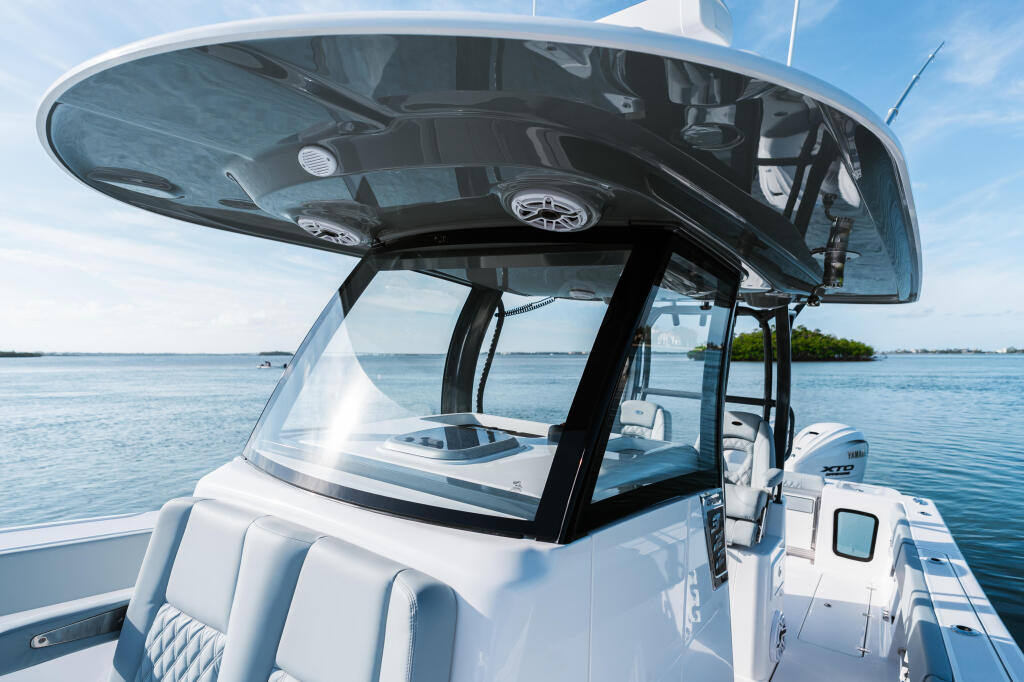 Hard-top boat helm with tinted windshield and control console overlooking calm coastal waters