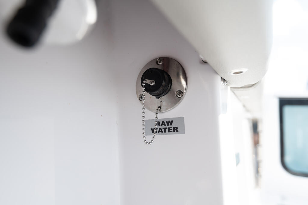 Raw water washdown outlet with pull-chain valve mounted on boat cabin exterior
